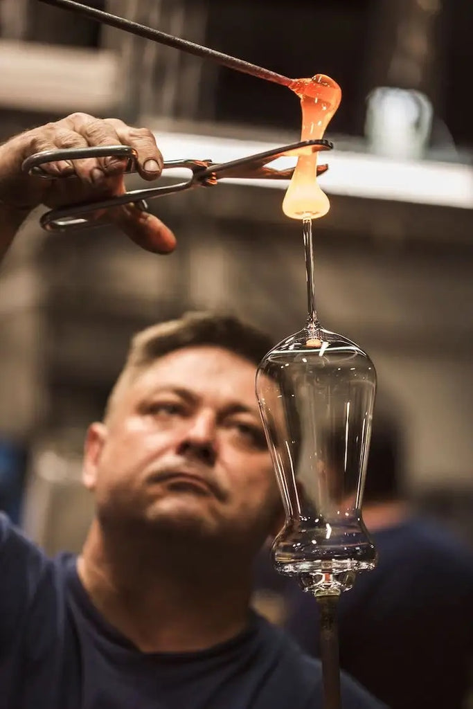 Man making a wine glass, cutting the stem from a hot hand blown piece of glass